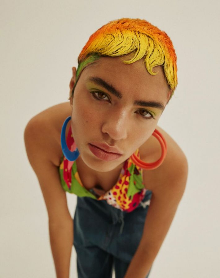 Zwei Personen in ausdrucksstarken, gemusterten Outfits in weiter Landschaft, in Bewegung